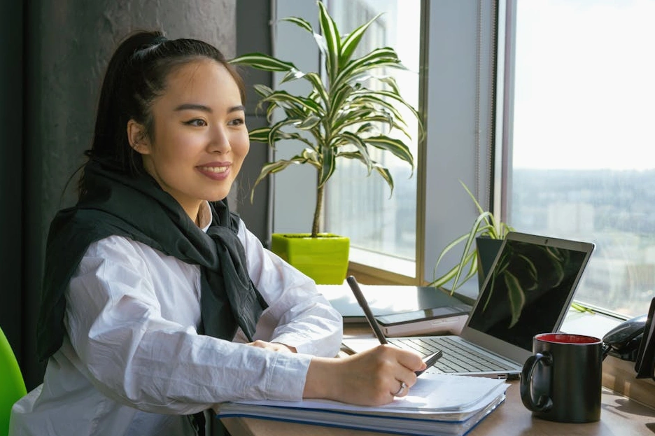Uśmiechnięta osoba ucząca się na laptopie w nowoczesnym biurze.